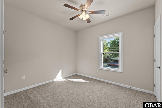 carpeted empty room featuring a ceiling fan, visible vents, and baseboards