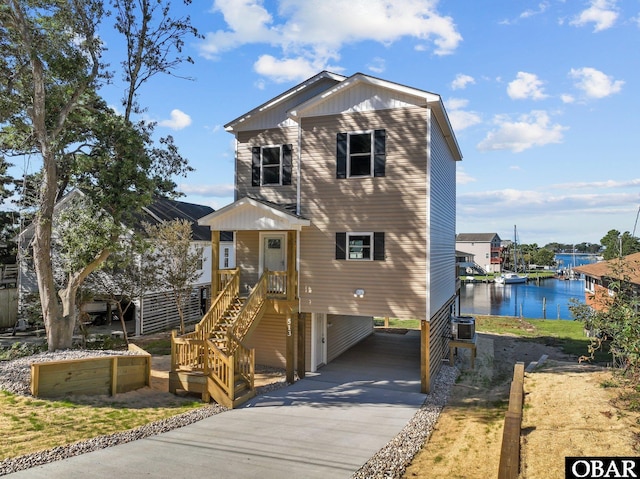 view of front facade with a carport, concrete driveway, a water view, and central AC