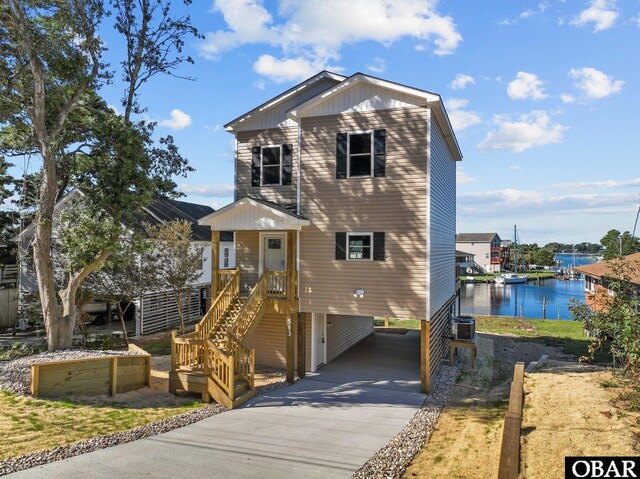 view of front facade with a carport, concrete driveway, a water view, and central AC