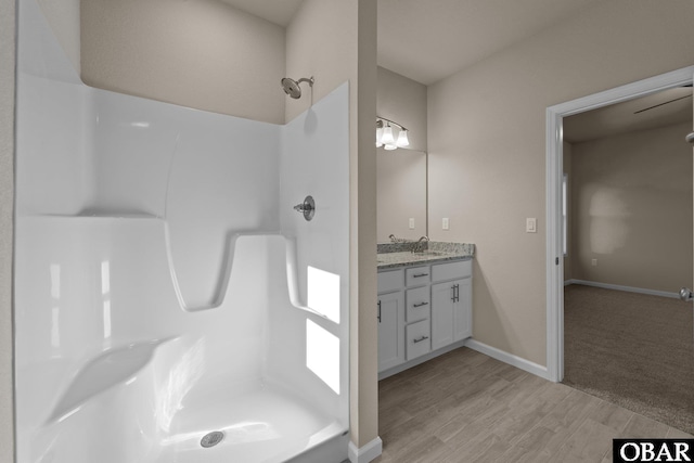 full bathroom featuring a stall shower, wood finished floors, vanity, and baseboards