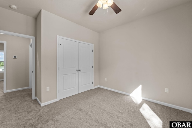 unfurnished bedroom with light carpet, ceiling fan, a closet, and baseboards