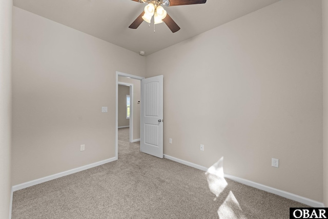 empty room featuring a ceiling fan, light carpet, and baseboards