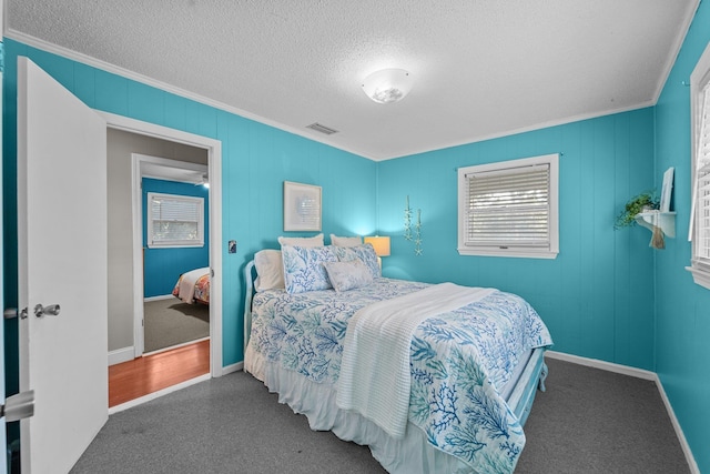 bedroom featuring a textured ceiling, visible vents, baseboards, dark carpet, and crown molding