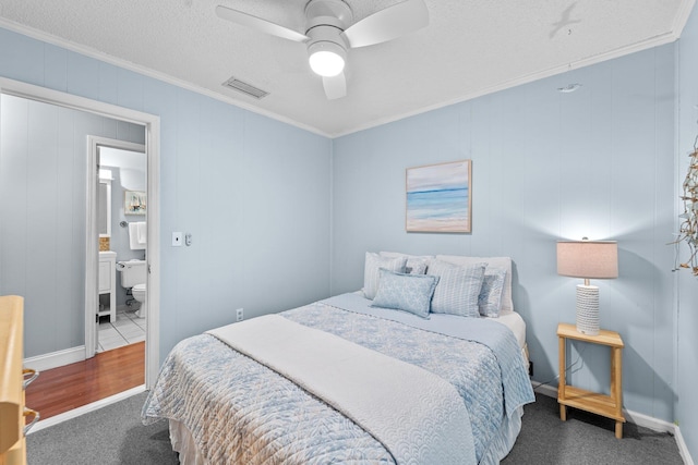 carpeted bedroom featuring visible vents, crown molding, a textured ceiling, and ensuite bathroom