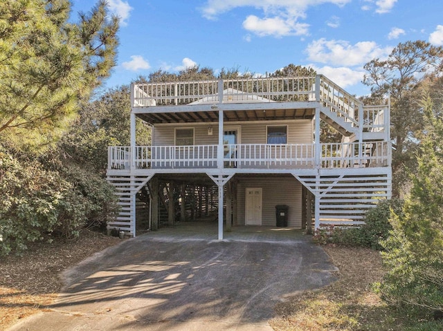 view of front of home with a carport, covered porch, driveway, and stairway