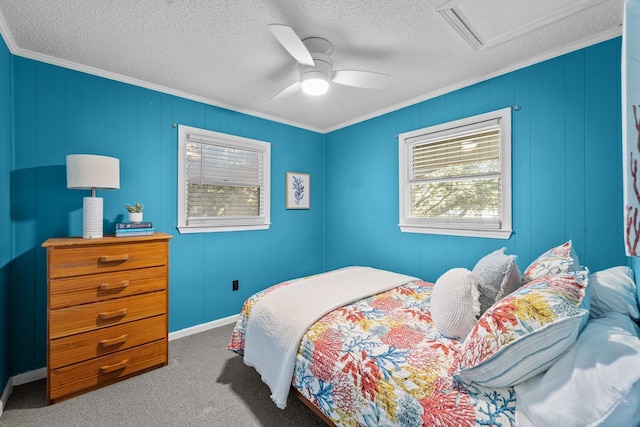 bedroom featuring a textured ceiling, carpet flooring, a ceiling fan, attic access, and crown molding