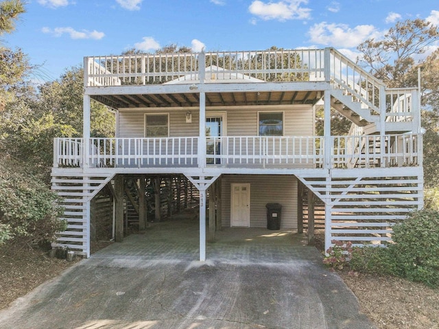 raised beach house with a porch, driveway, a carport, and stairs