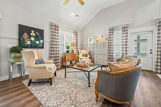 living area with wood finished floors, visible vents, a ceiling fan, vaulted ceiling, and baseboards