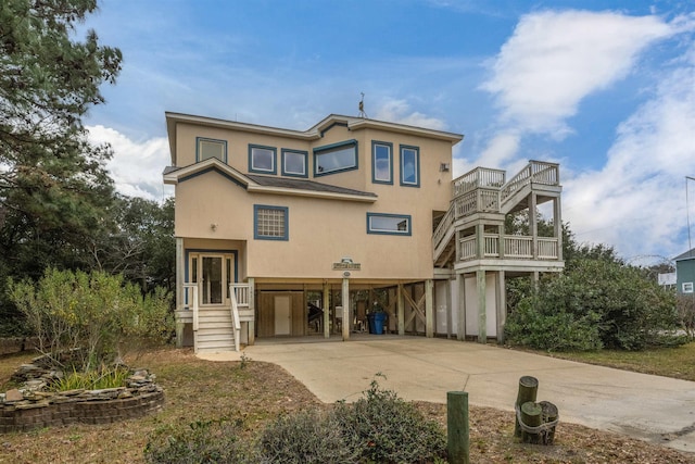 back of property with a carport, driveway, and stucco siding