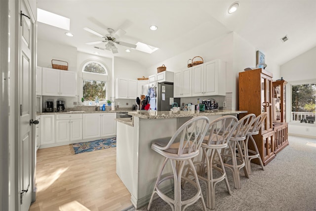 kitchen featuring vaulted ceiling with skylight, a wealth of natural light, and freestanding refrigerator