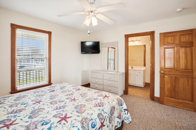 bedroom featuring a ceiling fan, light carpet, baseboards, and ensuite bathroom