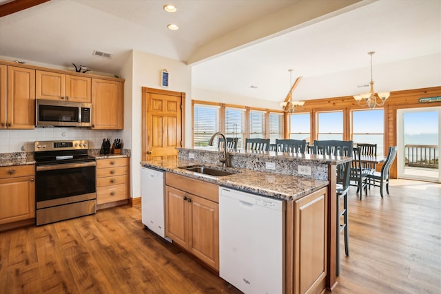 kitchen featuring a center island with sink, lofted ceiling, a breakfast bar, stainless steel appliances, and pendant lighting