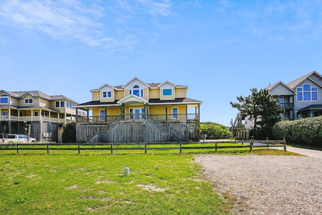 view of front facade with a residential view, stairway, covered porch, fence, and a front lawn