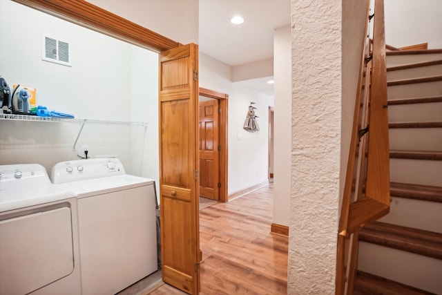 laundry room featuring laundry area, visible vents, washer and clothes dryer, baseboards, and light wood-style flooring