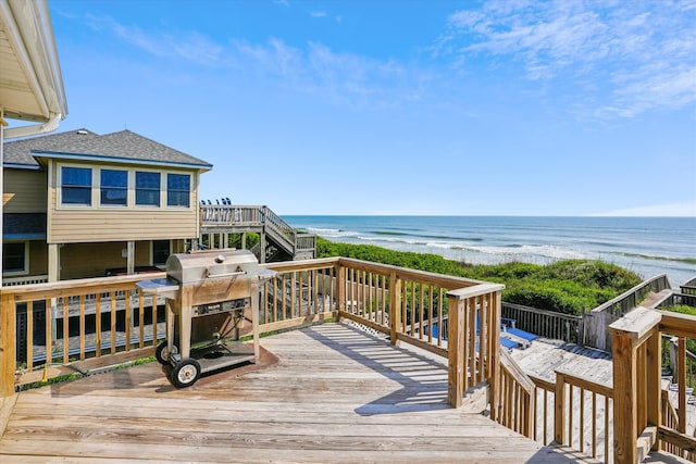 wooden deck with a view of the beach, a water view, and a grill