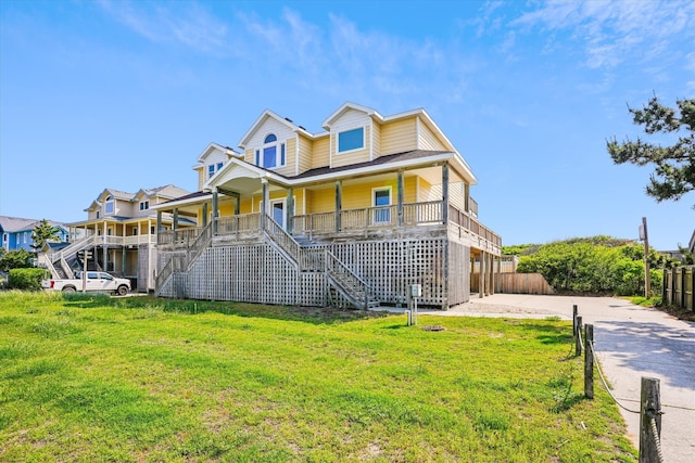 coastal inspired home featuring stairs, a porch, and a front yard