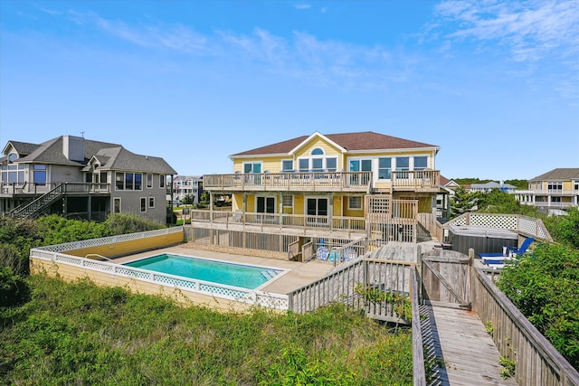 back of house featuring a deck, stairway, a residential view, and a fenced in pool