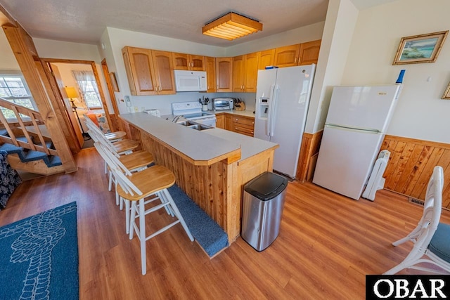 26509 Colony Dr Lot 6, Salvo, NC 27972 - kitchen with white appliances, light wood-style floors, light countertops, a peninsula, and a breakfast bar area