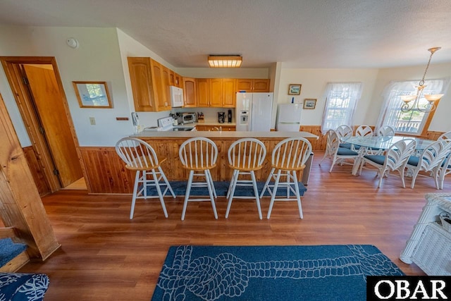 26509 Colony Dr Lot 6, Salvo, NC 27972 - kitchen with white appliances, a wainscoted wall, light wood-style floors, a breakfast bar, and light countertops