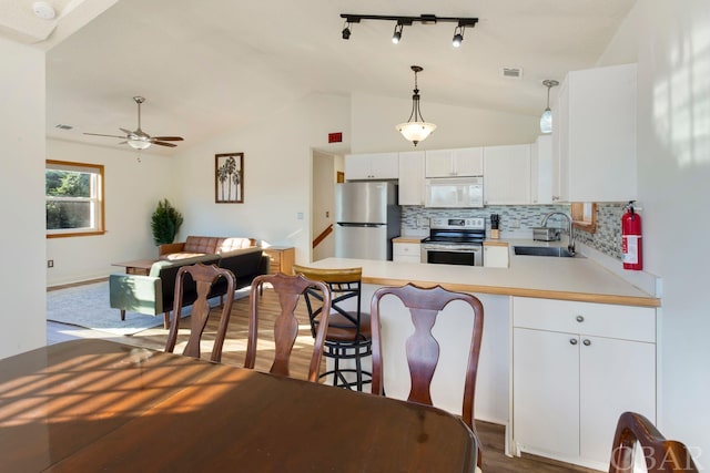 kitchen with stainless steel appliances, a sink, white cabinets, light countertops, and pendant lighting