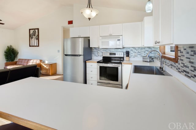 kitchen featuring stainless steel appliances, a sink, light countertops, and pendant lighting