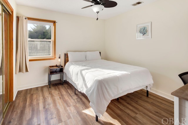 bedroom featuring ceiling fan, wood finished floors, visible vents, and baseboards