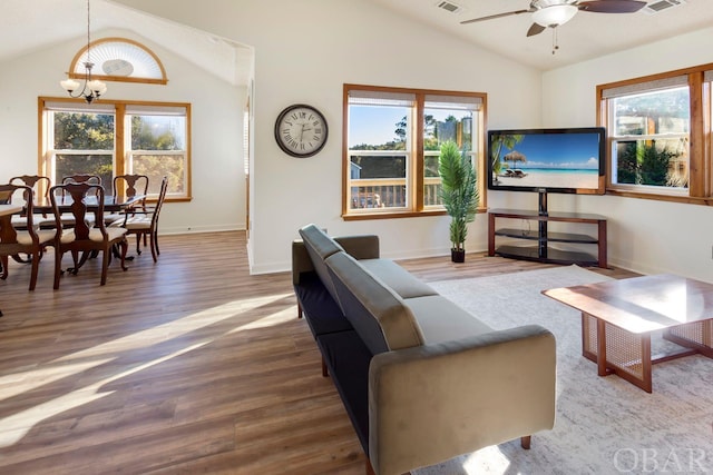 living area featuring baseboards, visible vents, vaulted ceiling, and wood finished floors