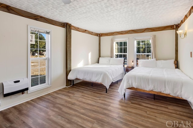 bedroom featuring heating unit and wood finished floors