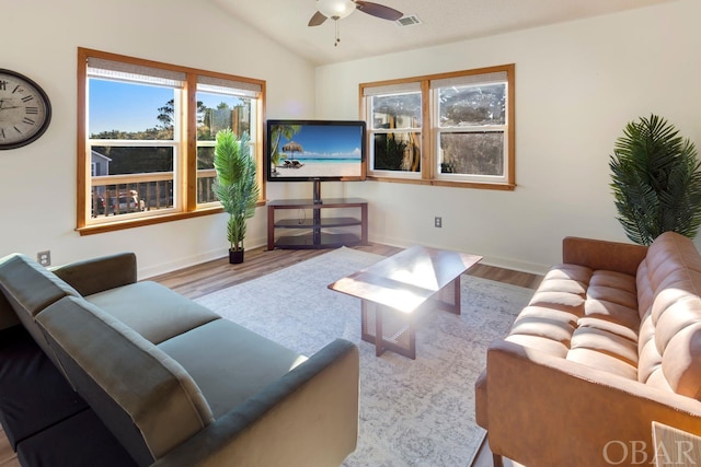 living area featuring light wood-style floors, lofted ceiling, visible vents, and a ceiling fan