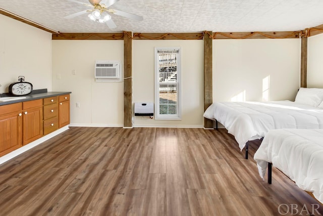 bedroom featuring a sink, baseboards, wood finished floors, and a wall mounted air conditioner