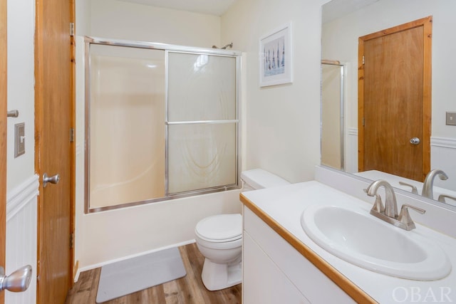 full bathroom with combined bath / shower with glass door, vanity, toilet, and wood finished floors