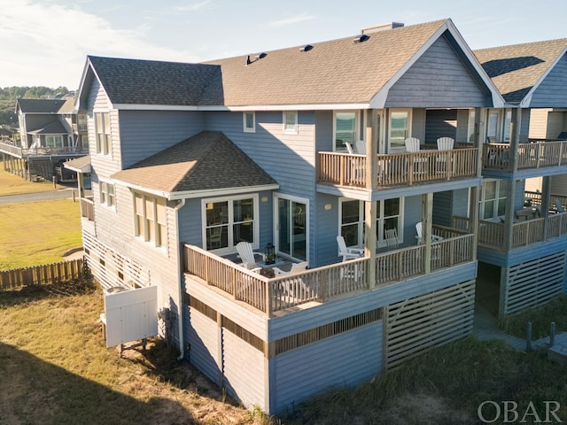 back of house featuring roof with shingles and a balcony