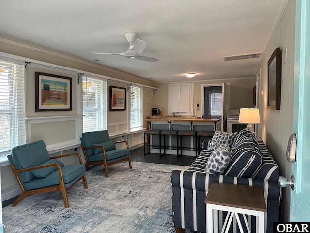 living room with visible vents, crown molding, ceiling fan, and wood finished floors