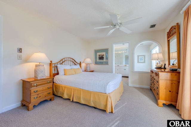 bedroom featuring visible vents, light carpet, arched walkways, and baseboards