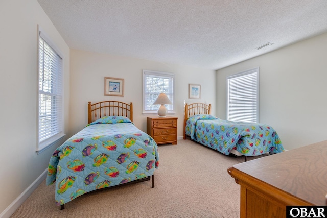 bedroom with visible vents, multiple windows, a textured ceiling, and carpet