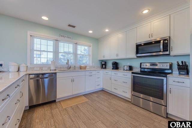 kitchen with a sink, stainless steel appliances, visible vents, and light wood-style flooring