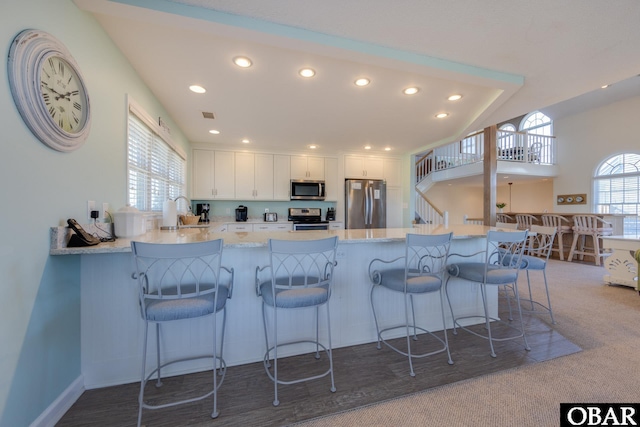 kitchen with a healthy amount of sunlight, appliances with stainless steel finishes, white cabinetry, and a peninsula