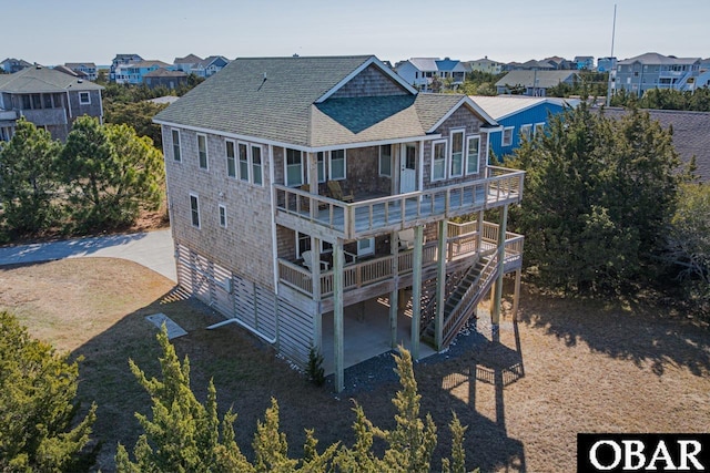 rear view of property with a shingled roof, driveway, a deck, and stairs