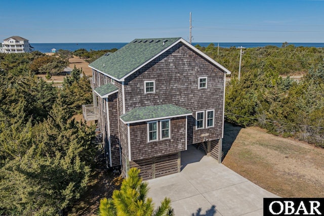 view of front of house featuring driveway, a shingled roof, and a water view