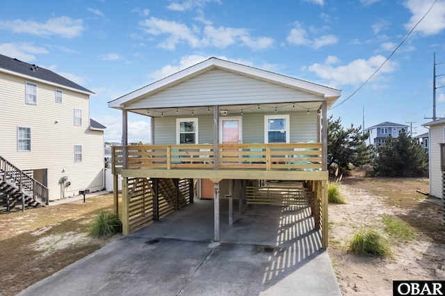 coastal home featuring a carport, covered porch, stairway, and concrete driveway