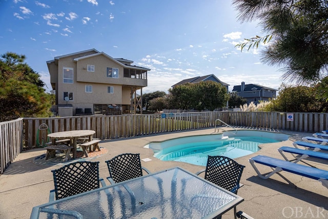 community pool featuring outdoor dining space, a patio area, and a fenced backyard