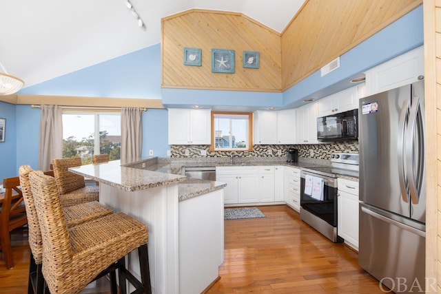 kitchen with appliances with stainless steel finishes, a breakfast bar area, visible vents, and white cabinets