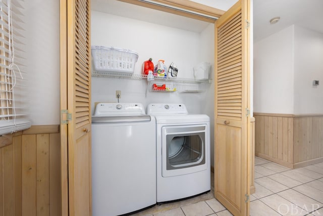 laundry area with laundry area, light tile patterned floors, a wainscoted wall, independent washer and dryer, and wood walls