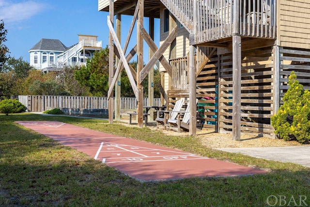 view of home's community with fence, shuffleboard, and a yard