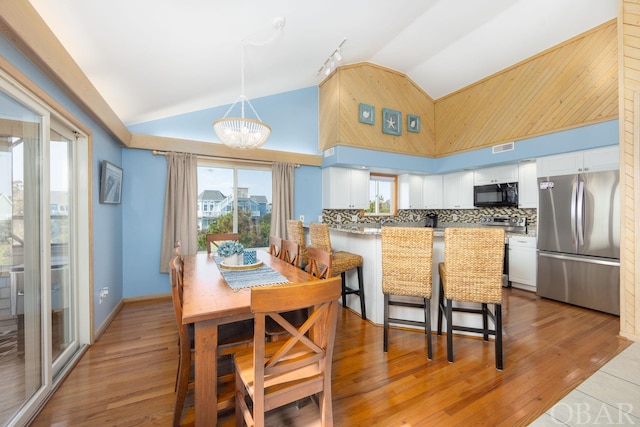 dining area featuring a view of city, high vaulted ceiling, and wood finished floors