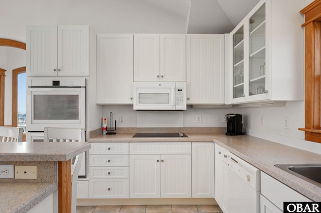 kitchen featuring white appliances, white cabinetry, glass insert cabinets, and light countertops