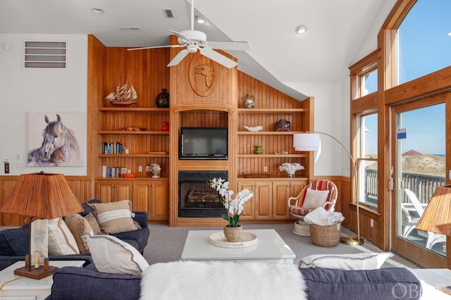 living room featuring light carpet, wooden walls, visible vents, built in features, and a fireplace