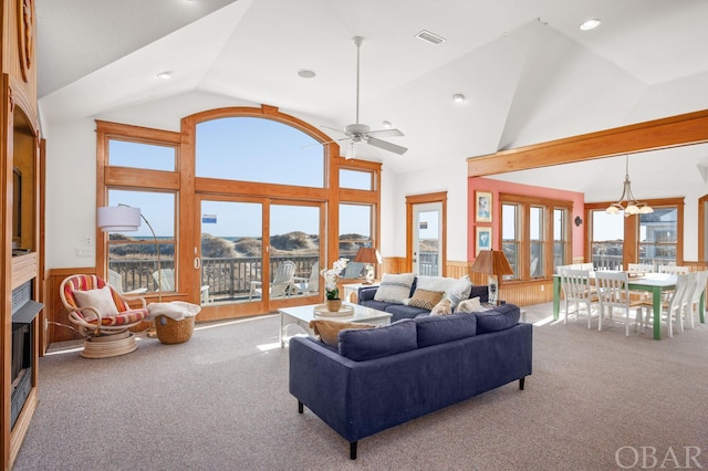 living room featuring carpet, a wainscoted wall, a mountain view, and ceiling fan with notable chandelier