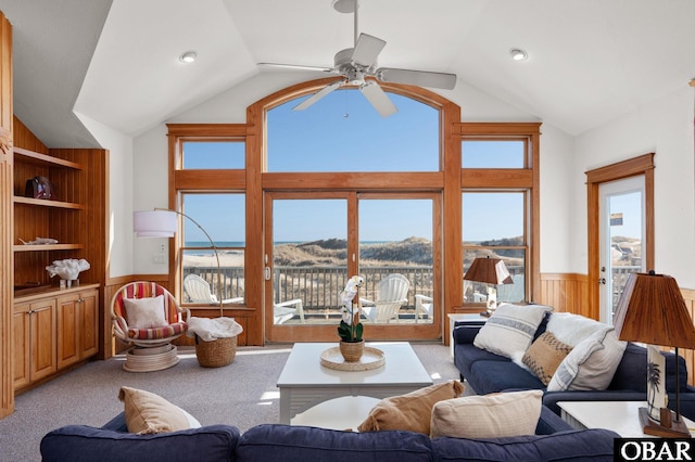 living room with light carpet, a wainscoted wall, built in shelves, and vaulted ceiling