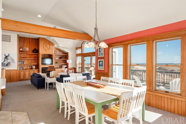 dining space featuring light carpet, wooden walls, visible vents, vaulted ceiling, and a fireplace